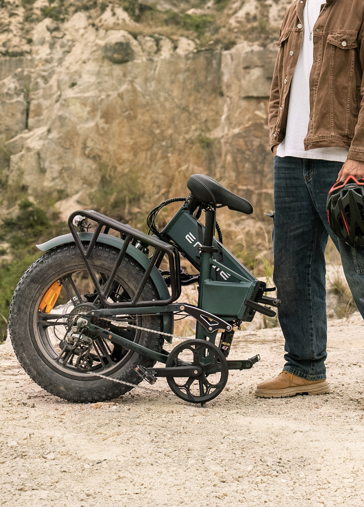 a man stands next to a folded mountain green engwe engine pro 2.0 electric bike